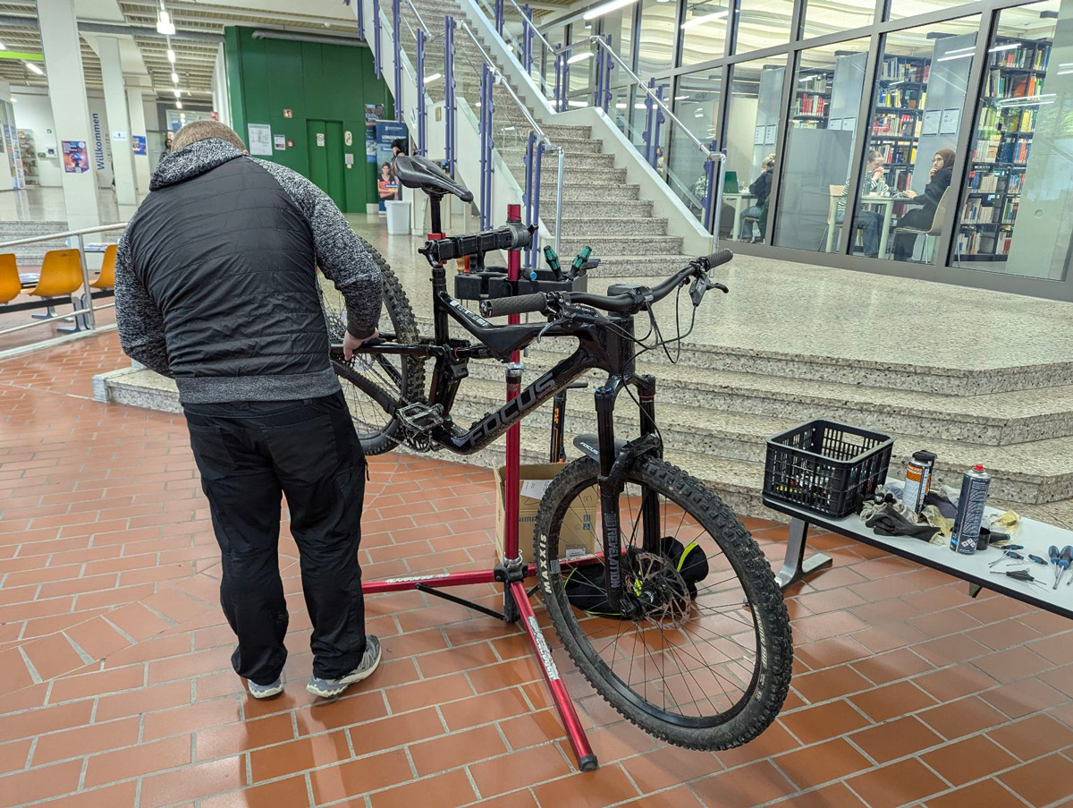 Mann steht vor Fahrrad und checkt es auf Funktionstüchtigkeit