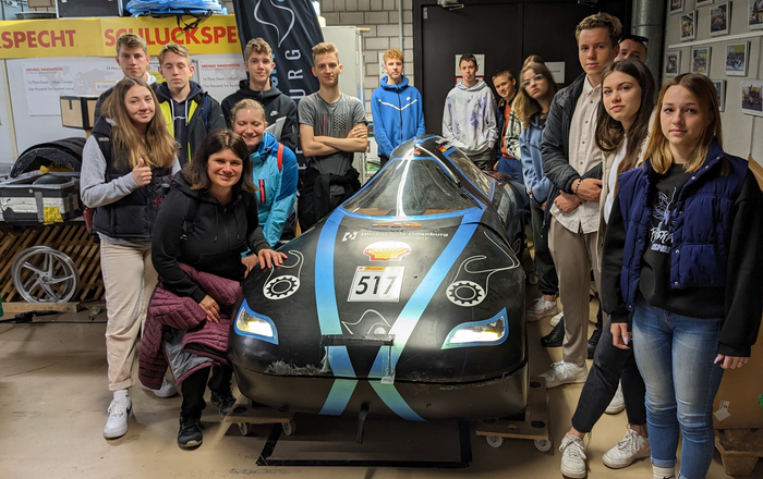 Die jungen Erwachsenen aus Slowenien stehen um ein Niedrigenergiefahrzeug des Teams Schluckspecht herum
