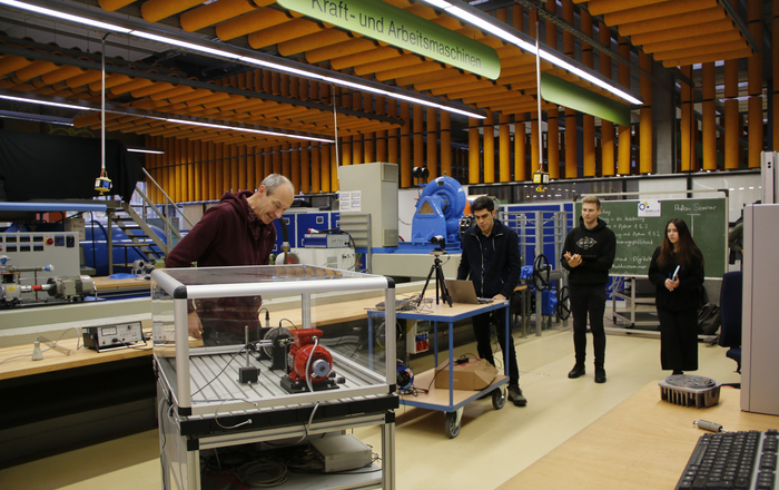 Gruppe steht im Labor um den Lavalläufer herum, es wird gefilmt