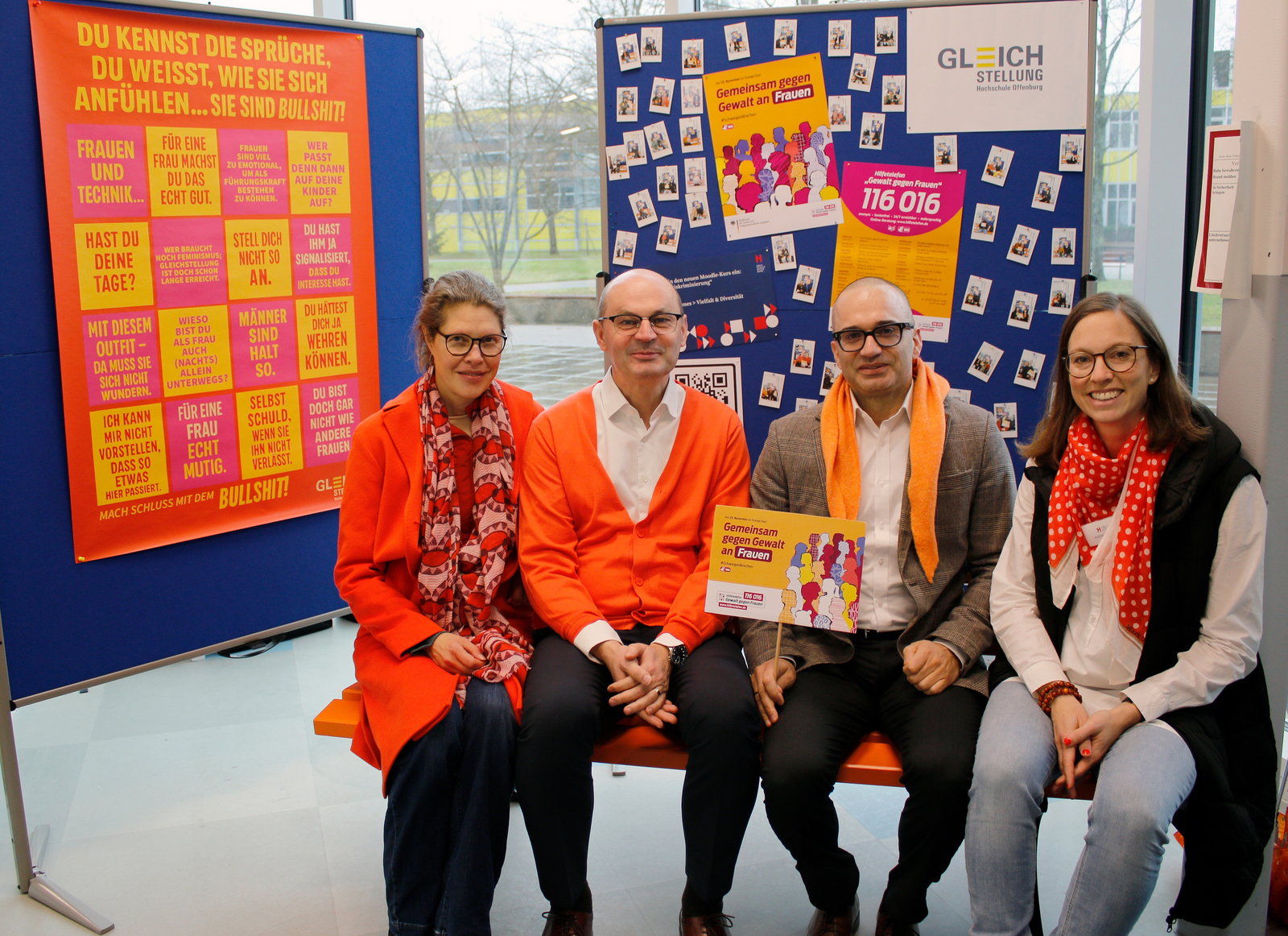 Tzwei Frauen und zwei Männer sitzen auf der orangenen bank