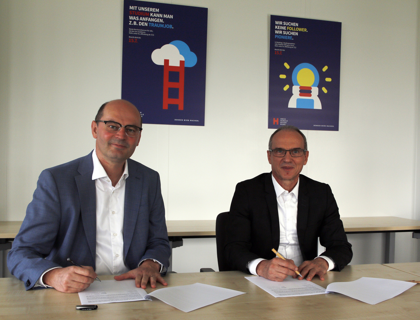 Hochschulrektor Prof. Dr. Stephan Trahasch und ECAM General Director Didier Desplanche sitzen am Tisch und unterzeichnen das Duoble-Degree-Abkommen