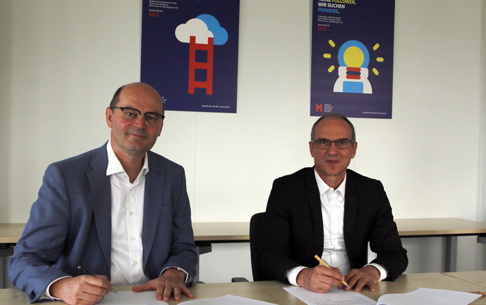 Hochschulrektor Prof. Dr. Stephan Trahasch und ECAM General Director Didier Desplanche sitzen am Tisch und unterzeichnen das Duoble-Degree-Abkommen