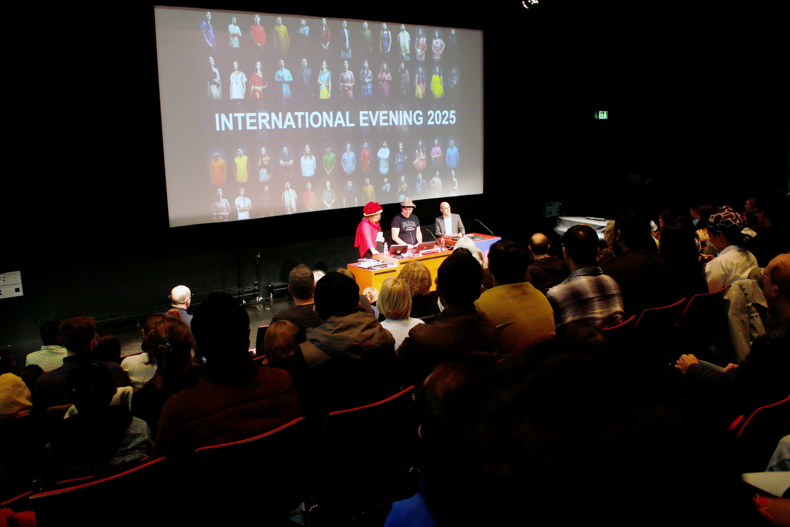 Drei menschn stehen vor einer Leinwand an einem rednerpult