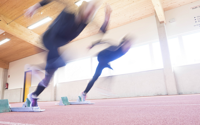 Zwei Sprinterinnen beim Start aus den Startblöcken mit Bewegungsunschärfe