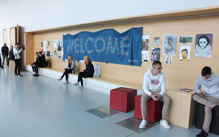 Erstsemester sitzen unter Willkommensbanner