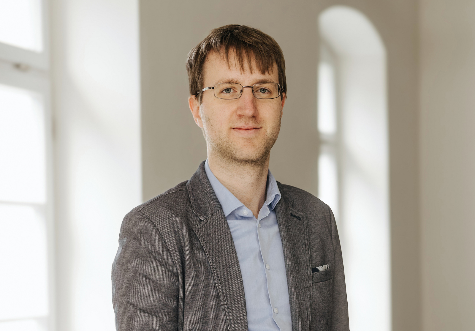 Ein Mann steht in einem Raum zwischen zwei Fenstern