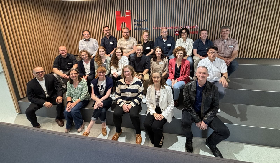 Ein Gruppenbild der Konferenzteilnehmenden, sitzend im Foyer des Gebäude A