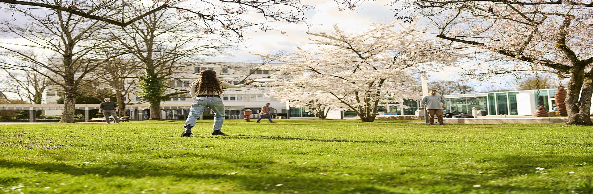 Studierende beim Frisbeespielen auf dem Campus