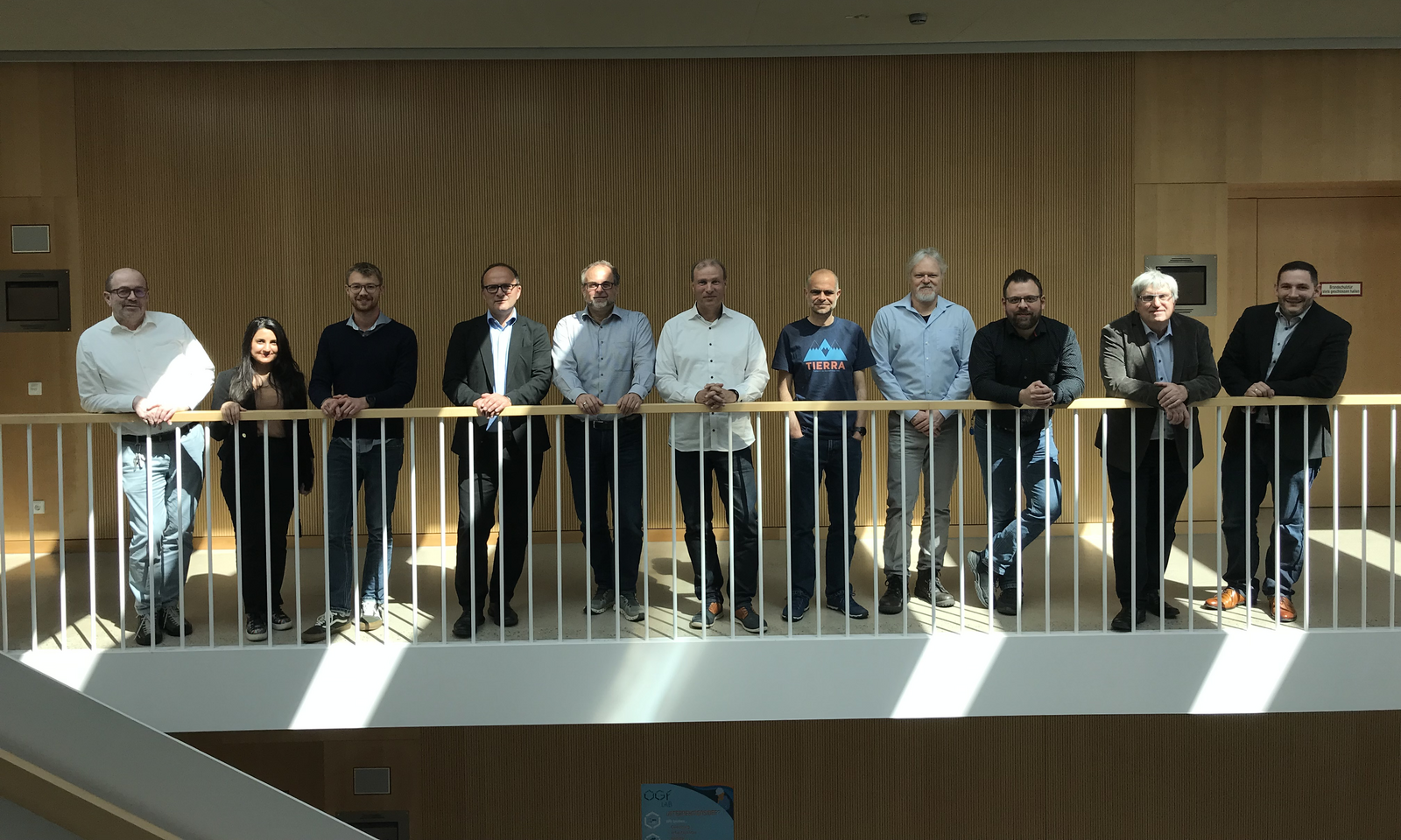 Gruppenbild der Teilnehmer des Projekttreffens: Die 11 Teilnehmer stehen nebeneinander an einem Geländer