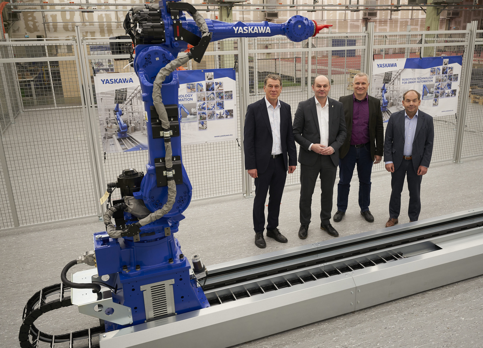 Vier Männer im Anzug stehen neben einem Roboter 