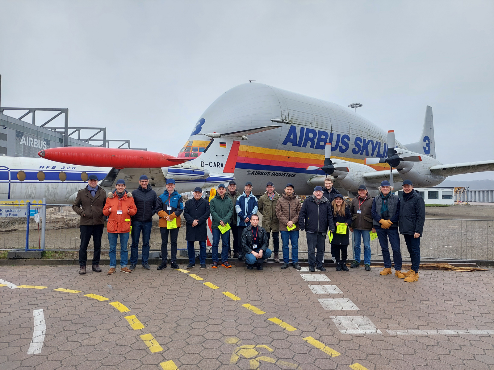 Die Projektbeteiligten stehen auf dem Firmengelände vor einem Airbus