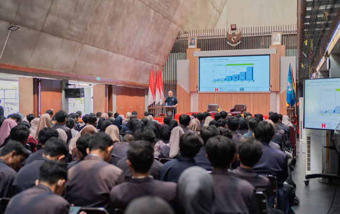 Ein Saal mit Zuhörern und einer Person an einem Rednerpult vor einer Leinwand