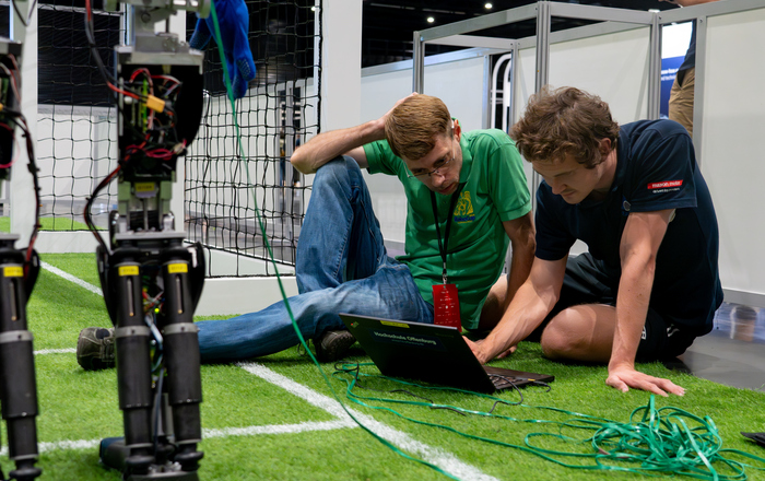 Team auf dem Rasen sitzend bei der Arbeit am Laptop