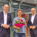 Die drei Personen stehn vor Gebäude D, Grit Köhler hält einen Blumenstrauß in der Hand