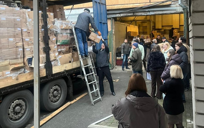 Menschen stehen neben einem mit Kartons beladenen Lastwagen und laden diesen aus
