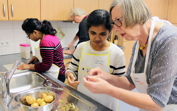Zwei internationale Studierende und zwei Seniorinnen in der Küche.