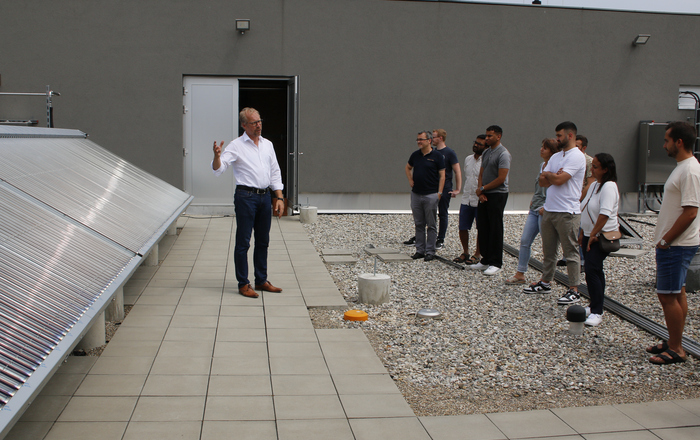 Das Bild zeigt Prof. Dr. Jens Pfafferott, links von ihm die Mega-Kollektoren und rechts die Zuhörenden