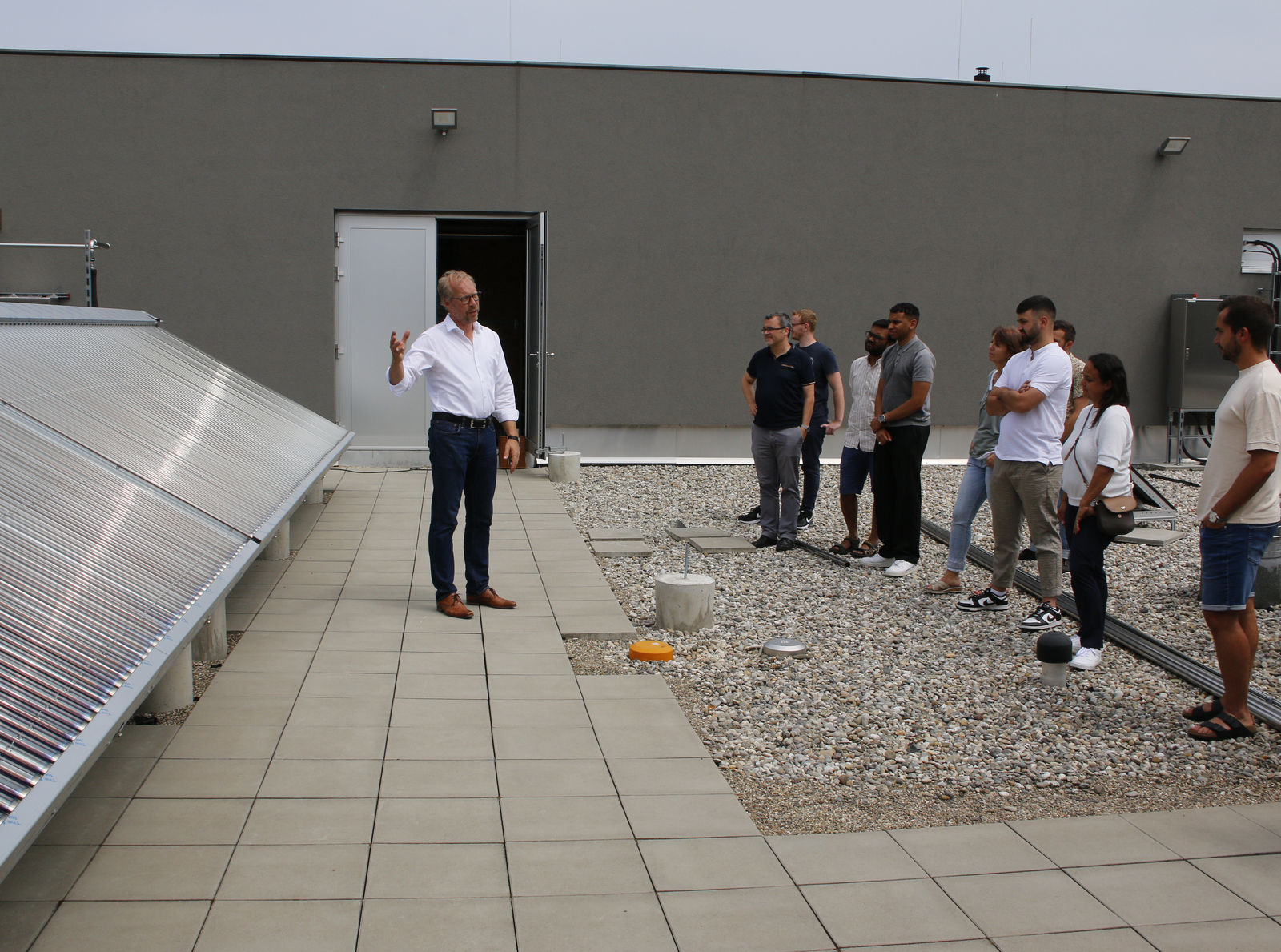 Das Bild zeigt Prof. Dr. Jens Pfafferott, links von ihm die Mega-Kollektoren und rechts die Zuhörenden