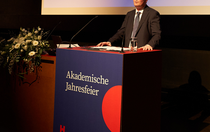Rektor Stephan Trahasch steht am Rednerpult. An diesem und auf einer Leinwand hinter ist Akademische Jahresfeier zu lesen
