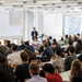 Zwei Männer stehen vor zahlreichen sitzenden Konferenzteilnehmenden
