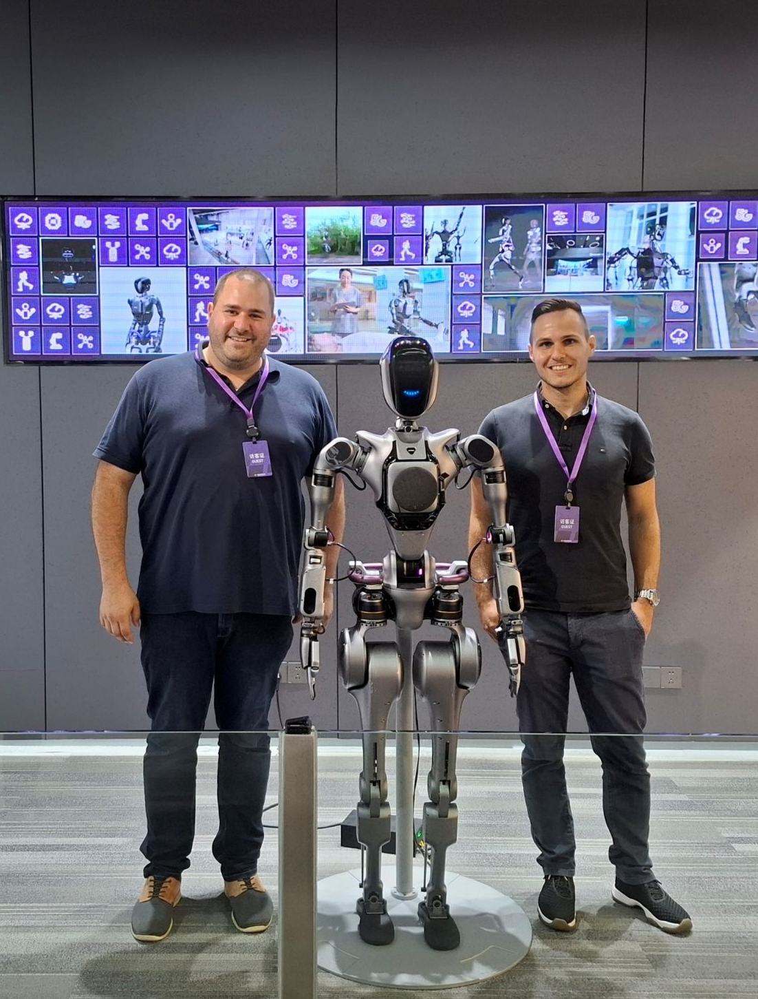 2025-08-07 Web-Meldung WLRI-Mitarbeitende in China Zwei junge Männer stehen rechts und links von einem humanoiden Roboter, im Hintergrund sind Bildschirme zu sehen