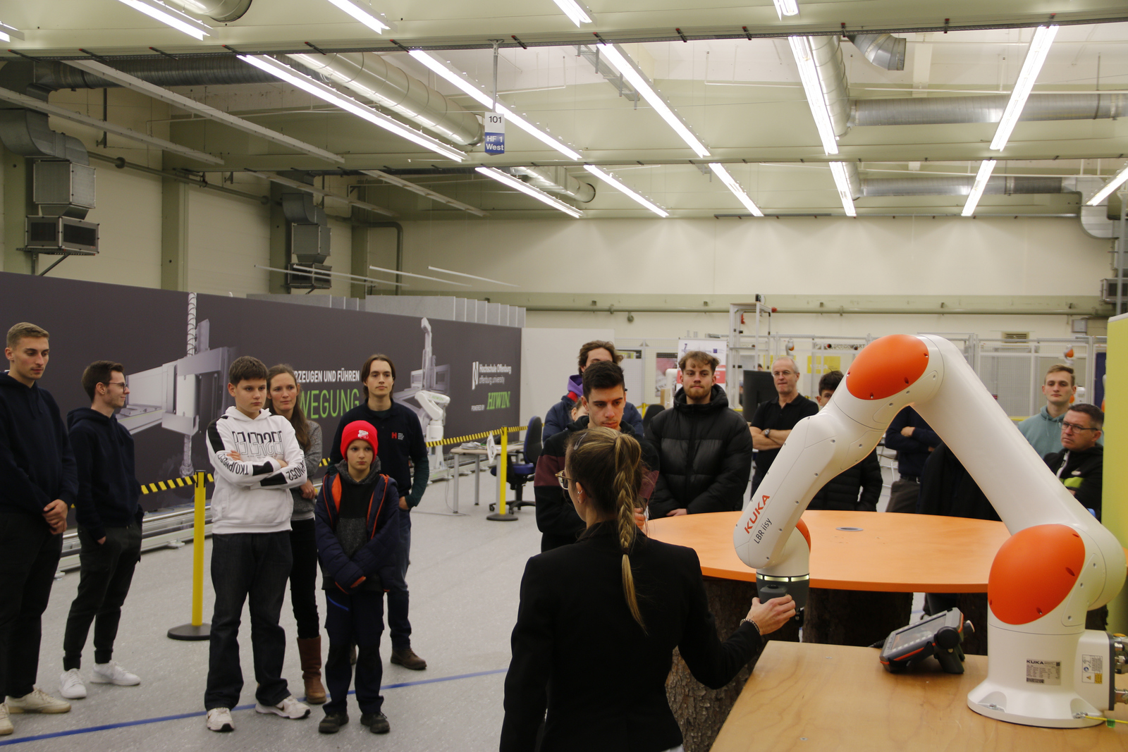 Jennifer Blöchle führt Schüler in die angewandte Robotik am WLRI ein Ein Mitarbeiter von WLRI zeigt einer Gruppe von Studenten einen Roboterarm