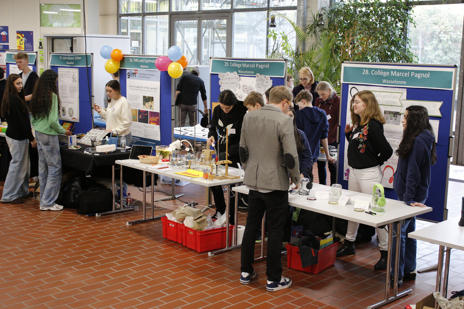 Schüler an präsentieren an Tischen mit Stellwänden dahinter ihre Forschungsarbeiten