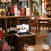 Hochschullehrpreisträger Prof. Dr. Thomas Seifert (rechts) und die neue Professorin für E-Commerce Simone Braun (links) sitzen in einem Café und reden mit dem neuen Professor für Audiogestaltung und Sounddesign Markus Birkle (Mitte), der via Computerbildschirm zugeschaltet ist.