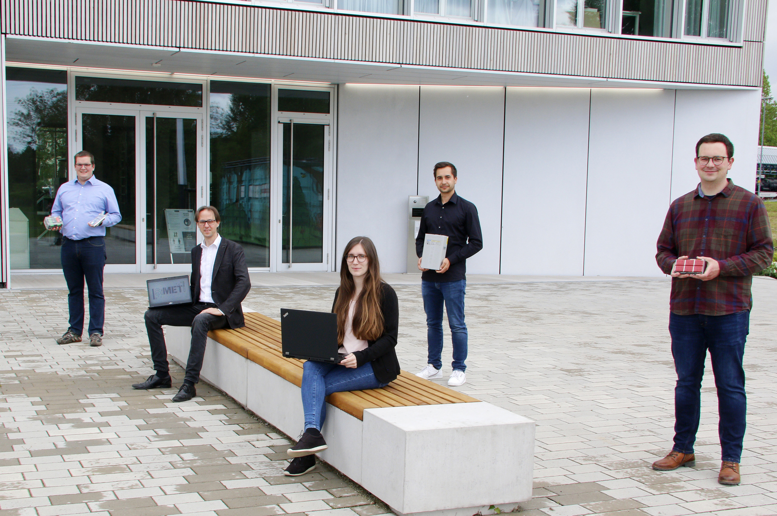 Prof. Dr. Wolfang Bessler und die Doktorandin Jennifer Brucker (sitzend von links) sowie die Doktoranden Michael Quarti, David Schmider und Jonas Braun (stehend von links) vor dem RIZ Energie.