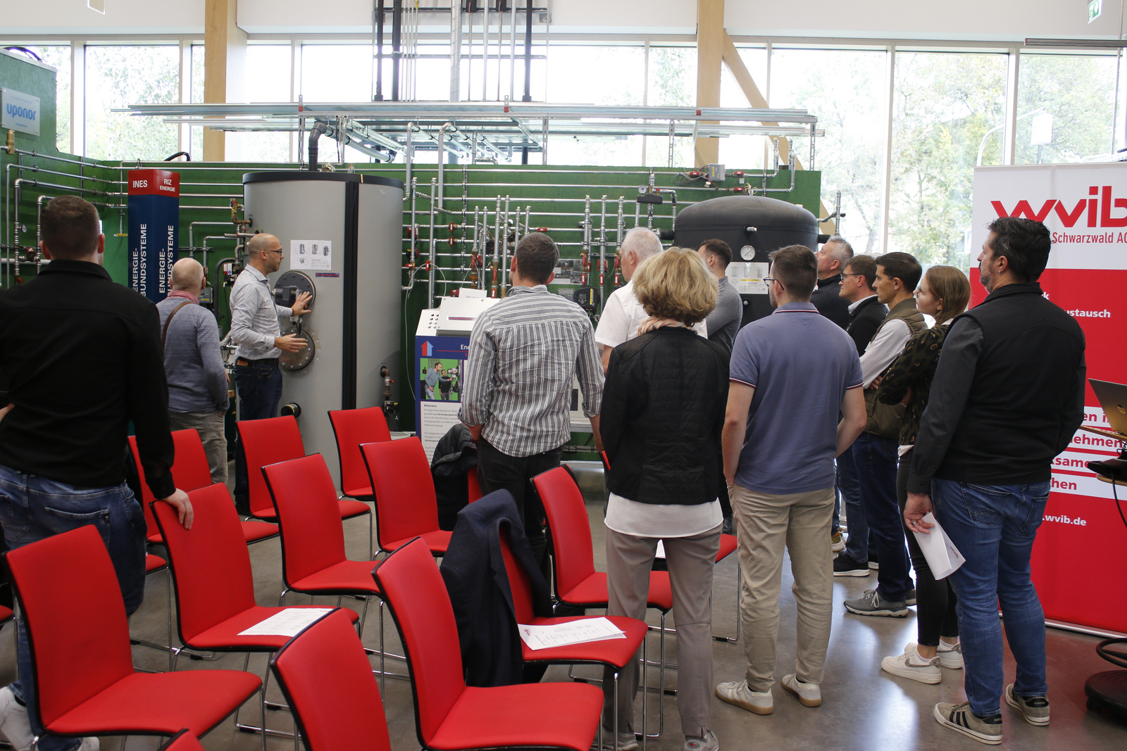 Menschen stehen um eine Heizungsanlage herum, ein Mann erklärt etwas