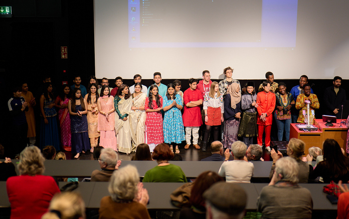 Gruppenfoto aller Akteure teilweise in ihrer traditionellen Kleidung auf der Bühne 
