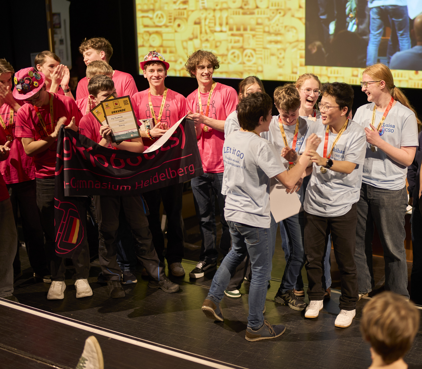 zwei Teams aus jungen Menschen jubeln auf einer Bühne