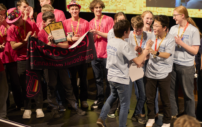 zwei Teams aus jungen Menschen jubeln auf einer Bühne