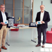 Rektor Prof. Dr. Winfried Lieber (rechts) übergibt Studiendirektor Martin Stern (links), dem stellvertretenden Schulleiter der kaufmännischen Schulen, Masken im Foyer des D-Gebäudes.