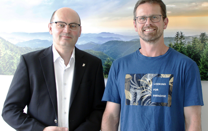 Rektor Prof. Dr. Stephan Trahasch (links) und Christoph Wieland (rechts) vor einem Schwarzwaldbild.