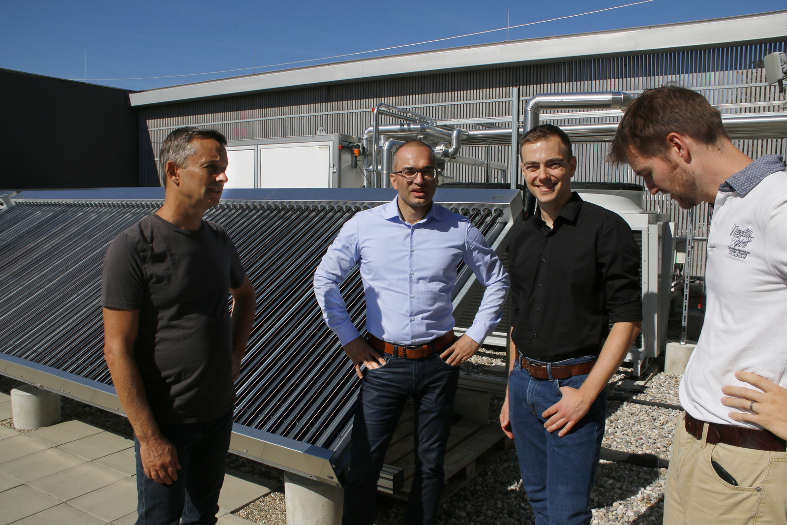 Die vier Herren vom Green Office vor der Solarthermieanlage auf dem RIZ Energie