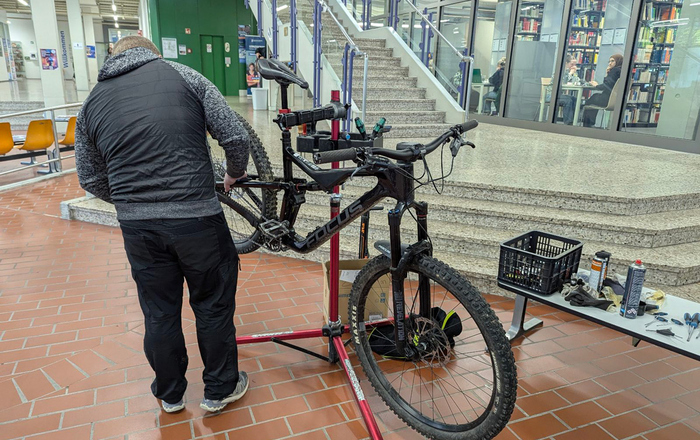 Mann steht vor Fahrrad und checkt es auf Funktionstüchtigkeit
