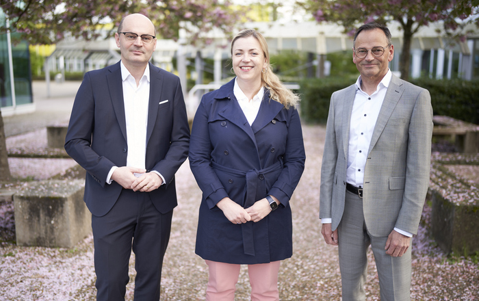 Stephan Trahasch, Ulrike Kahle-Roth und Klaus Erdrich (von links) stehen unter blühenden Bäumen auf dem Campus. 