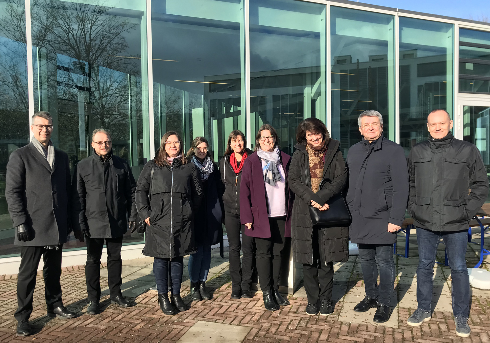 Gruppenfoto bei strahlendem Sonnenschein in Winterjacken vor der Mensa