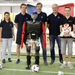Gruppenfoto mit Robotern vor einem Tor in dem eine Frankreichflagge hängt, Sweaty hat eine blaue Baseball-Kappe mit dem weißen Schriftzug France auf.
