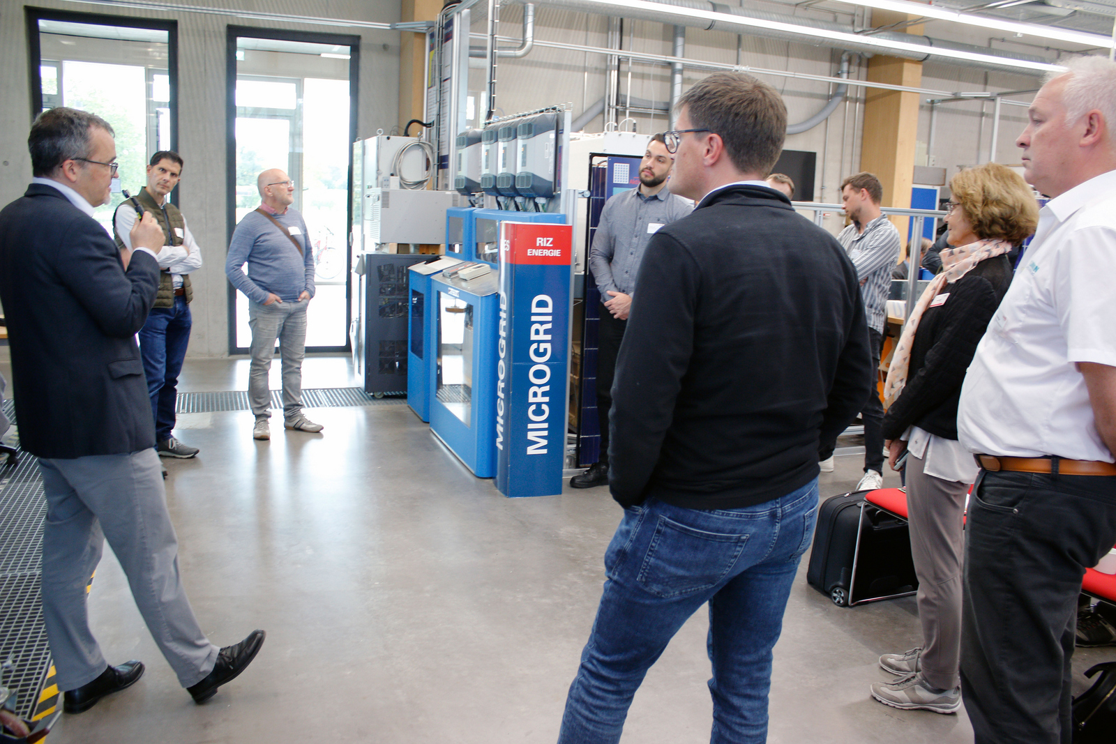 Eine Gruppe Menschen steht um eine MicroGrid-Anlage herum