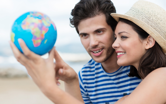 Eine Frau hält eine Weltkugel in ihrer Hand und zeigt einem Mann etwas darauf.