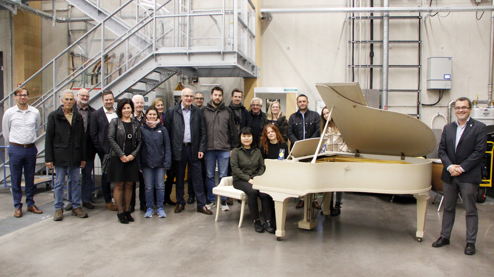 Gruppenfoto, die anwesenden VdF-Mitglieder haben sich um den Flügel herum aufgestellt an dem die Pianistinnen sitzen.