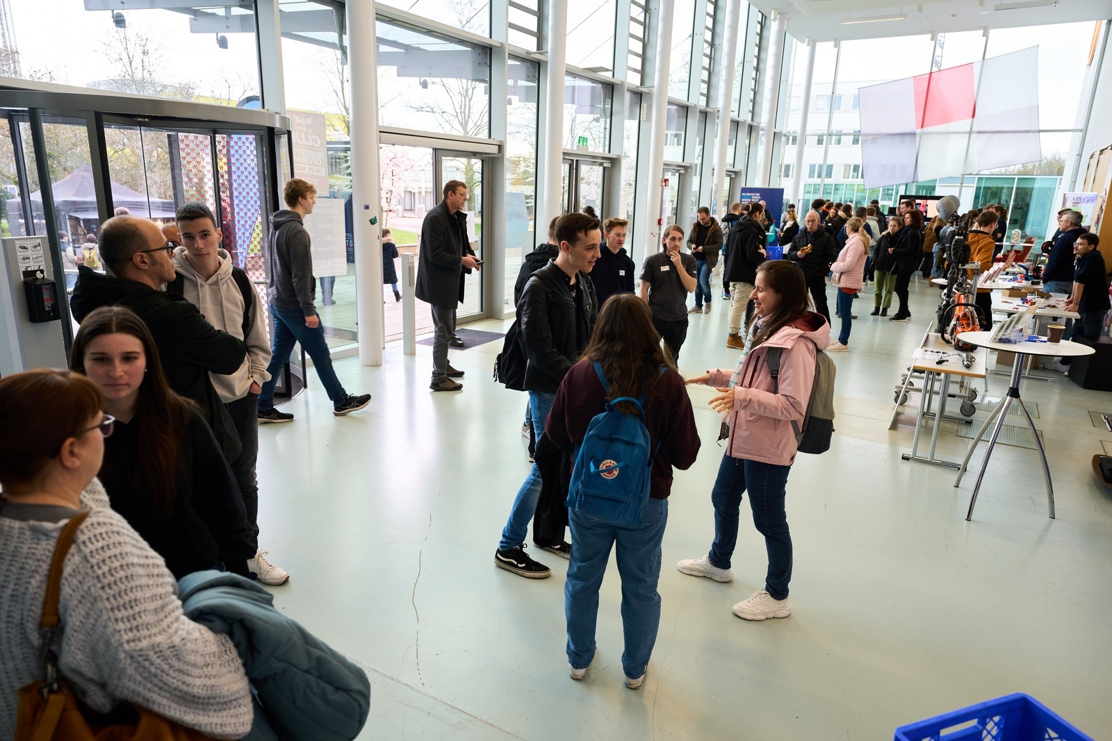 Menschen an Infoständen im Foyer von Gebäude D