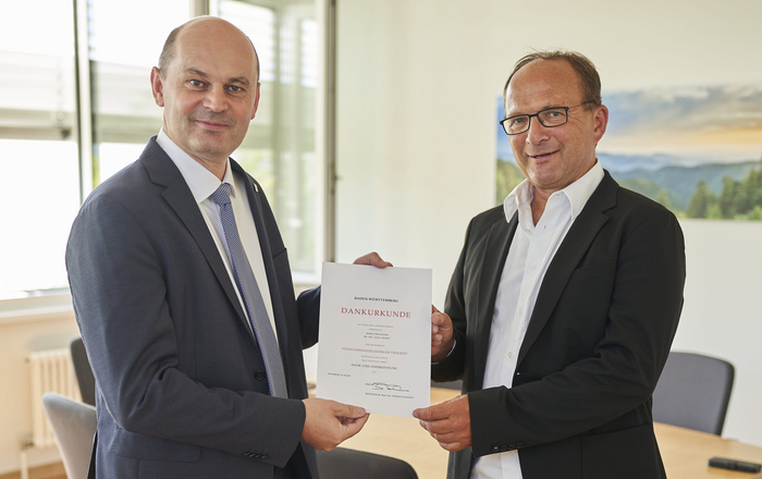 Rektor Prof. Dr. Stephan Trahasch (links) überreicht in seinem Büro Jubilar Prof. Dr. Axel Sikora (rechts) die Urkunde. 