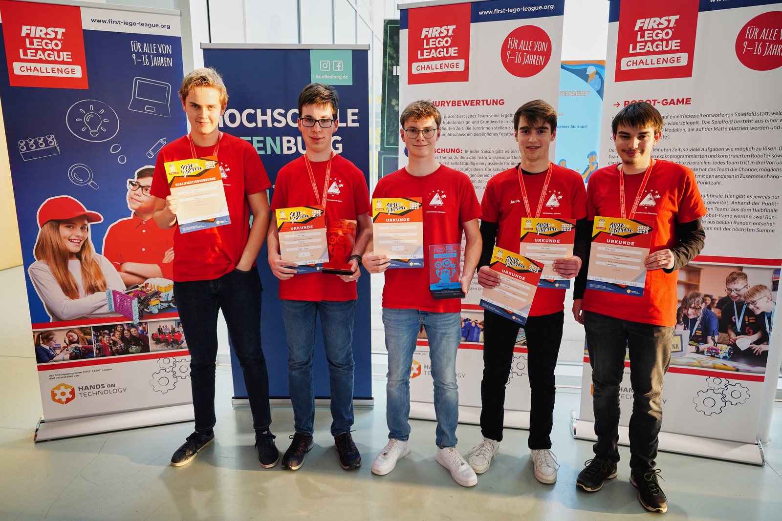 Die fünf Jungen in ihren roten Team-T-Shirts präsentieren ihre Urkunden und den Pokal