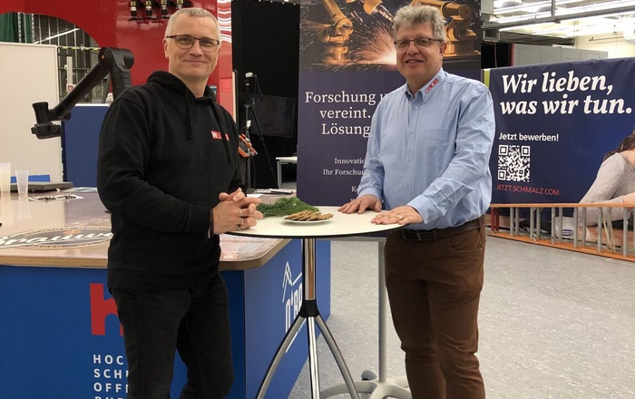 Two men stand at a tall table
