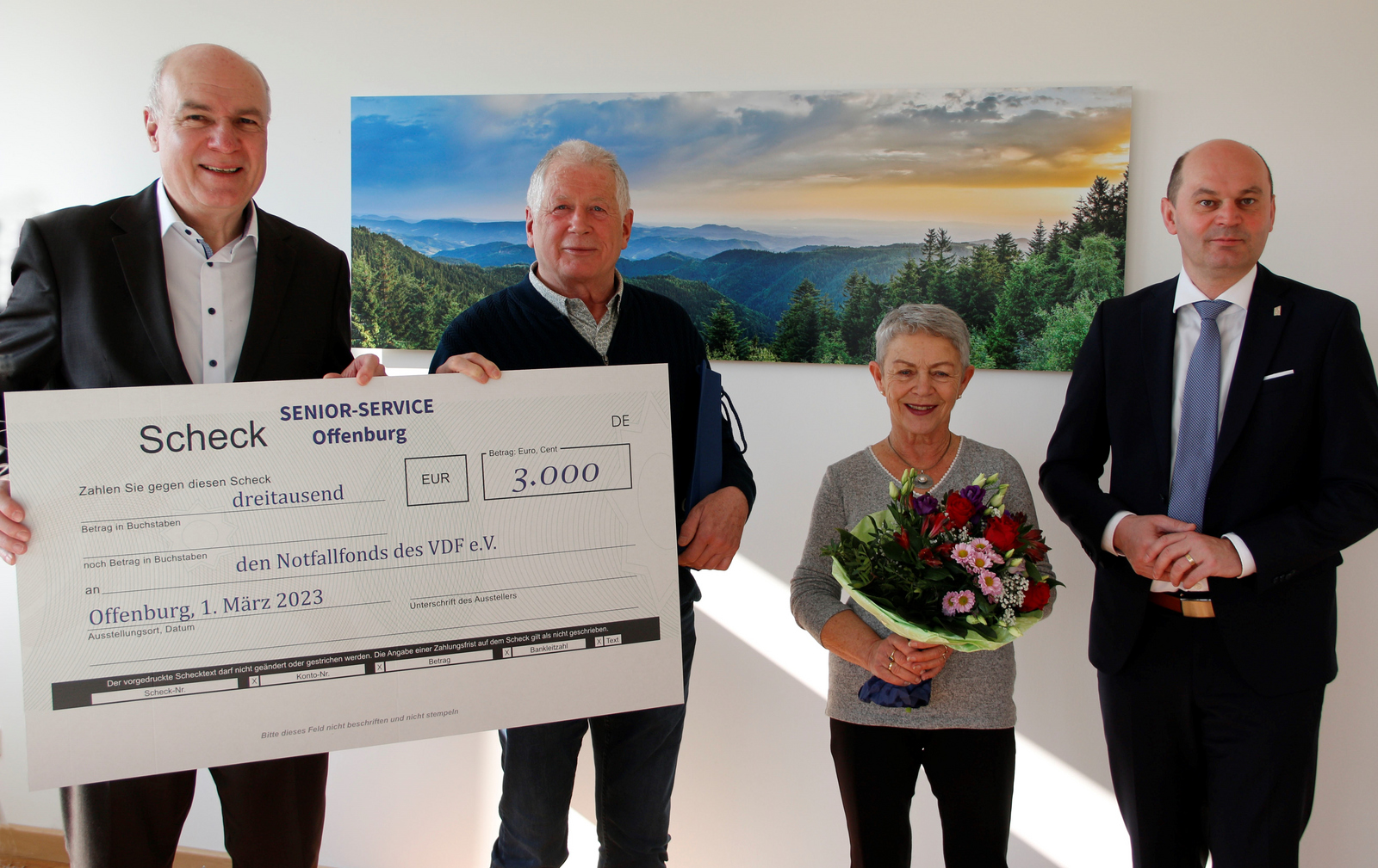 Gruppenfoto mit Spendenscheck vor Schwarzwaldbild