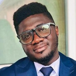 CME_Alumni-Statement_Stephen Osei Kuffour Porträt von Stephen Osei Kuffour im blauen Anzug mit Krawatte und Brille