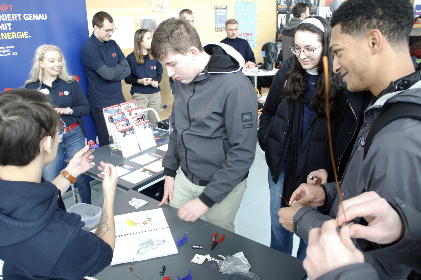 2023-11-23 Web-Meldung Studieninfotag Mitmachangebot Schüler basteln an Tisch mit Batterien und Drähten